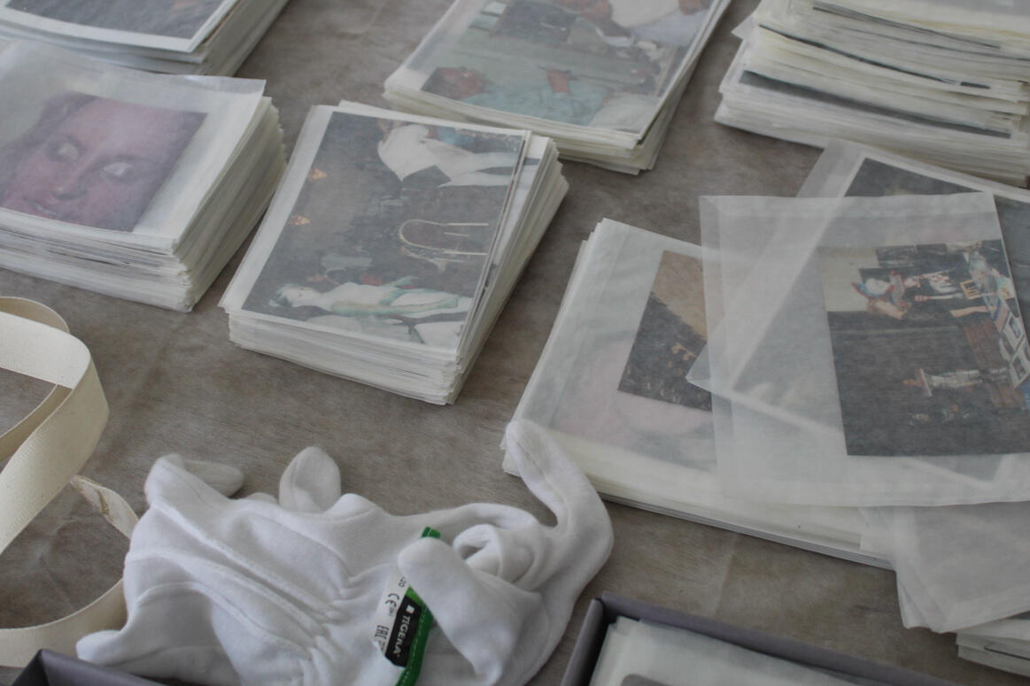 In dem Bild sind mehrere Stapel von Fotos zu sehen, die in Transparentpapier eingewickelt sind und sorgfältig auf einem Tisch arrangiert wurden. In dem Bild sind mehrere Stapel von Fotos zu sehen, die in Transparentpapier eingewickelt sind und sorgfältig auf einem Tisch arrangiert wurden.